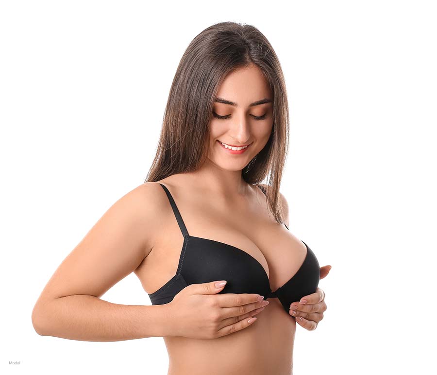 Young woman in black bra holding her breasts up to a higher level